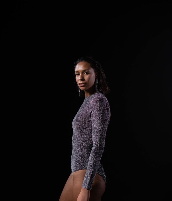 Athlete performing a deep stretching yoga pose in a dark studio.